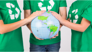 Pessoas com camisetas verdes e com símbolo da reciclagem em destaque seguram o globo