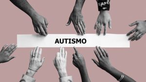 Diversas mãos tocando faixa que diz "autismo" em fundo rosa